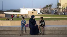 Sekeluarga memakai masker untuk mencegah penyebaran virus corona sambil menikmati malam mereka di tepi cornice, di Rabat, Maroko, Selasa (22/9/2020). (AP Photo / Mosa'ab Elshamy)