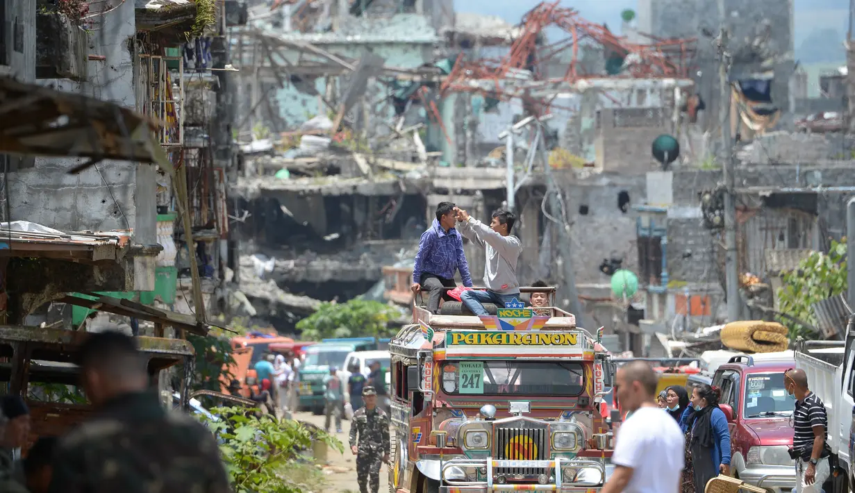 Warga mengambil gambar bangunan yang hancur dari atas mobil saat memasuki Kota Marawi, Mindanao, Filipina, Minggu (1/4). Mereka hampir setahun mengungki akibat pertempuran militer Filipina dengan militan ISIS. (TED ALJIBE/AFP)