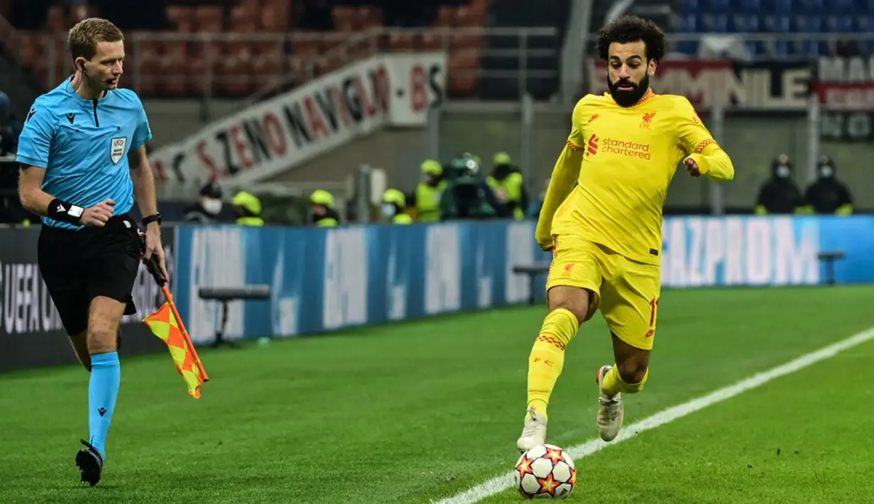Pemain Liverpool Mohamed Salah (kanan) mengontrol bola di sebelah asisten wasit Jan de Vries saat melawan AC Milan pada pertandingan sepak bola Grup B Liga Champions di Stadion San Siro, Milan, Italia, 7 Desember 2021. Liverpool menang 2-1. (MIGUEL MEDINA/AFP)