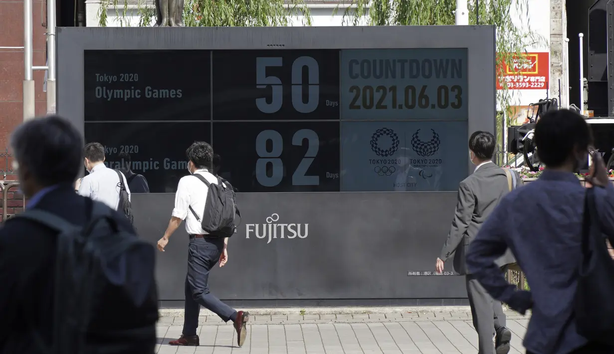 Orang-orang berjalan di dekat jam hitung mundur untuk Olimpiade dan Paralimpiade Tokyo 2020 di dekat stasiun Shimbashi untuk menandai 50 hari sebelum dimulainya Olimpiade Musim Pana di Tokyo, Kamis (3/6/2021). (AP Photo/Kntaro Komiya)