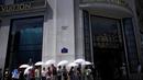 Orang-orang menggunakan payung untuk melindungi diri dari sinar matahari saat mereka mengantre untuk memasuki toko Louis Vuiton di jalan Champs Elysee, di Paris, Prancis, Rabu (18/5/2022). Cuaca panas diperkirakan akan berlangsung selama beberapa hari di seluruh Prancis. (AP Photo/Christophe Ena)