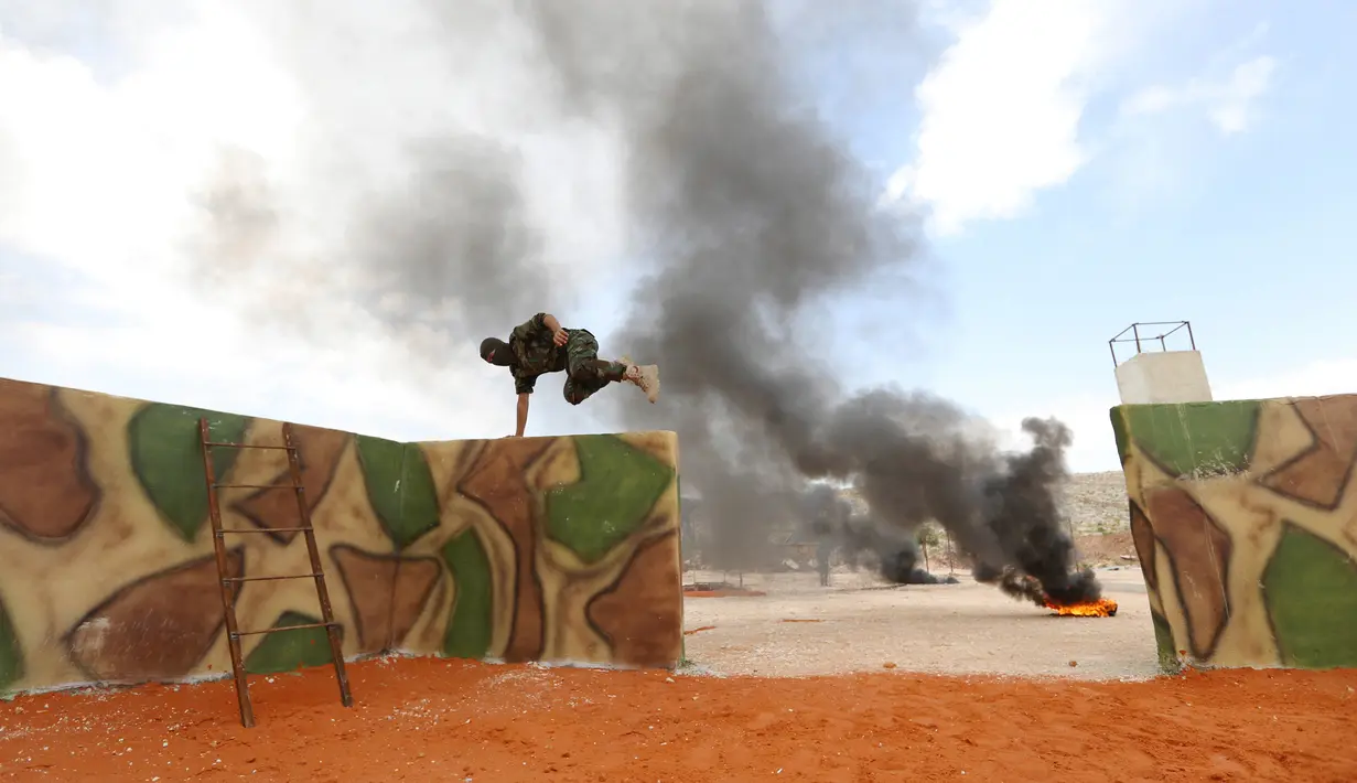 Seorang pejuang Jaysh al-Izza (the Army of Glory) melompati rintangan saat melakukan latihan di kota Idlib, Suriah (9/4). (AFP/Omar Haj Kadour)