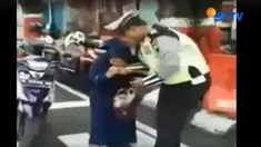 Sadar dirinya direkam oleh sesama polisi, sang ibu malah melanjutkan aksinya dengan memamerkan uang hingga memukul dada petugas.