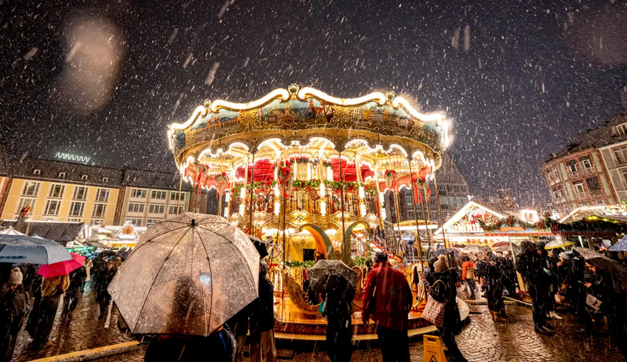 Salju turun saat Pasar Natal tradisional dengan komidi putar dibuka di Frankfurt, Jerman, Senin (27/11/2023). Pasar Natal adalah tradisi Eropa yang telah dilakukan selama berabad-abad. (AP Photo/Michael Probst)