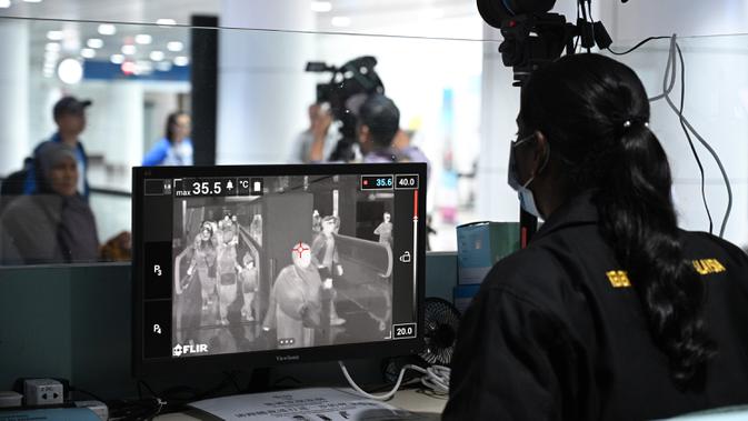 Petugas kesehatan memeriksa 'thermal scanner' untuk mendeteksi suhu tubuh penumpang yang tiba di Bandara Internasional Kuala Lumpur pada Selasa (21/1/2020). Pemerintah Malaysia mulai mengoperasikan alat pemindai suhu tubuh merespons penyebaran virus korona yang kian masif di China. (MOHD RASFAN/AFP)