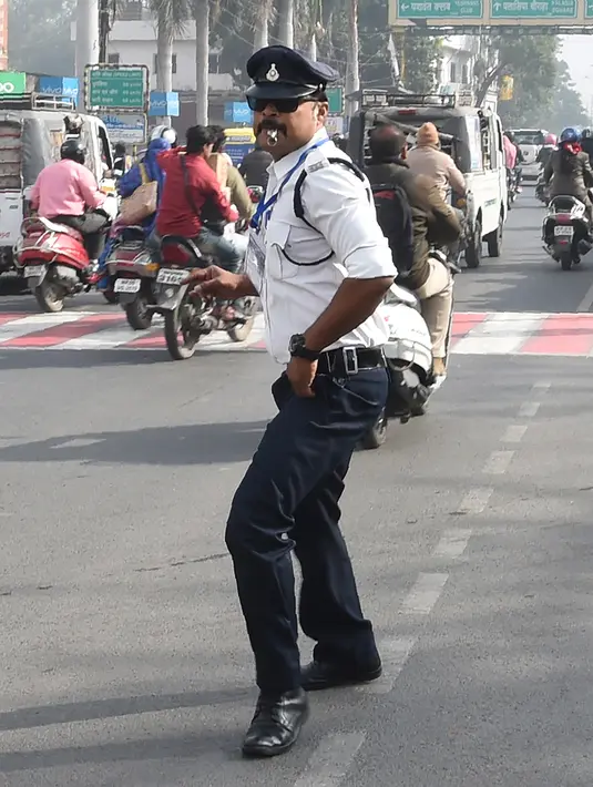 Polisi lalu lintas India Ranjeet Singh melakukan tarian "moonwalking" saat mengarahkan lalu lintas di persimpangan Indore, India (22/12). Cara Ranjeet Singh mengatur lalu lintas menjadi menarik perhatian warga sekitar. (AFP Photo/Indranil Mukherjee)