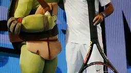 Petenis Swiss, Roger Federer berpose dengan salah satu karakter kura - kura ninja di Melbourne Park, Australia, (16/1). Acara ini juga sebagai kampanye penyelenggaraan Turrnamen  tenis Australia Terbuka yang dimulai 18 januari 2016. (REUTERS / Issei Kato)