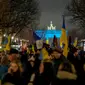 Para pengunjuk rasa tiba di Gerbang Brandenburg, diterangi dengan warna bendera Ukraina, saat demonstrasi untuk menandai peringatan satu tahun invasi besar-besaran Rusia ke Ukraina di Berlin, Jerman, 24 Februari 2023. (AP Photo/Markus Schreiber)