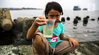 Seorang anak menunjukkan air dari Kali Adem, Muara Angke, Jakarta Utara, Sabtu (2/10/2021). Teluk Angke dan Ancol yang ada di wilayah Jakarta Utara dilaporkan tercemar paracetamol dengan konsentrasi tinggi. (Liputan6.com/Faizal Fanani)