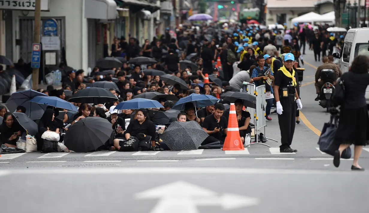Sejumlah warga mengenakan pakaian hitam memadati jalan saat saat menunggu pemakaman mendiang Raja Thailand Bhumibol Adulyadej di Bangkok (25/10). (AFP Photo/Anthony Wallace)