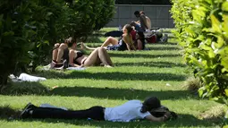 Sejumlah orang berjemur sambil menikmati matahari musim panas di dekat air mancur Trocadero di Paris, Senin (19/6). Suhu temperatur di ibu kota Prancis ini mencapai 36 derajat celcius. (AFP Photo / LUDOVIC MARIN)