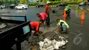 Sejumlah pekerja memperbaiki jalan yang rusak akibat banjir di kawasan Kelapa Gading. Sebelumnya, kawasan ini terendam banjir setinggi 80 cm hingga memutuskan arus lalu lintas, Jakarta, Jumat (13/2/2015). (Liputan6.com/Faisal R Syam)