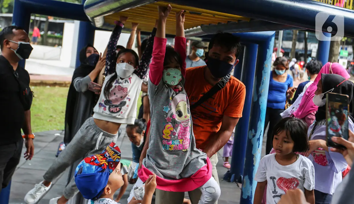 Anak-anak didampingi orang tua mereka bermain di Taman Puring, Jakarta, Minggu (9/1/2022). Di tengah ancaman penyebaran covid-19 varian Omicron dan pemberlakukan PPKM level 2, masyarakat tetap melakukan aktivitas pada akhir pekan di luar rumah. (Liputan6.com/Johan Tallo)