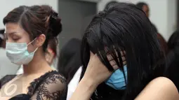 Seorang perempuan WNA menutup wajahnya saat diamankan di Kantor Imigrasi Kelas I Khusus Jakarta Barat, Sabtu (7/1). Mereka diduga melanggar keimigrasian yang berprofesi sebagai penari, pemandu lagu, Pekerja Seks Komersil (PSK). (Liputan6.com/Johan Tallo)