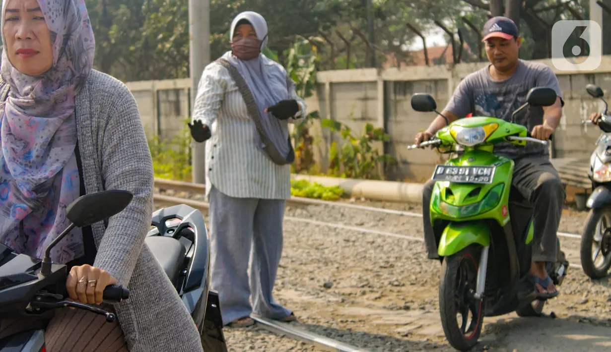 Neng Mulyani atau Bu Neng (tengah) mengatur lalu lintas di perlintasan kereta yang berada di Batuceper, Tangerang, Jumat (15/11/2019). Selama 8 tahun, wanita paruh baya ini mengabdikan waktunya untuk menjaga perlintasan. (Liputan6.com/Magang/Andika Zulfikar)