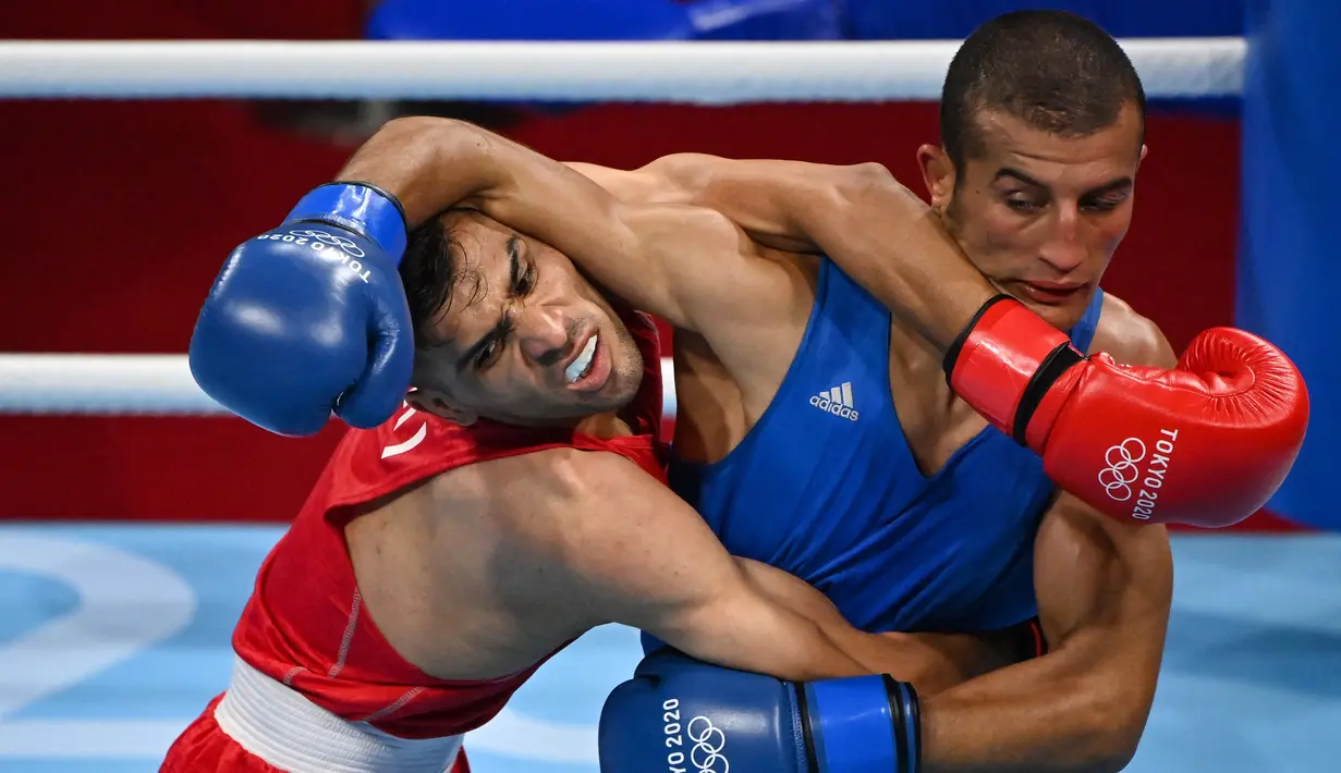 Petinju Iran Daniyal Shahbakhsh (merah) melawan petinju Maroko Mohamed Hamout dalam pertandingan tinju putra (52-57kg) pada Olimpiade Tokyo 2020 di Kokugikan Arena di Tokyo pada 24 Juli 2021. (AFP/ Luis Robayo)