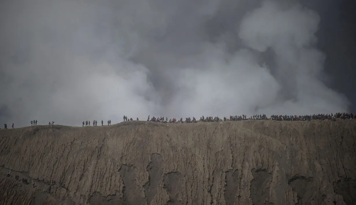 Wisatawan dan anggota suku Tengger mendaki Gunung Bromo saat Festival Yadnya Kasada di Probolinggo, Jawa Timur (10/7). Warga Tengger melakukan ritual lempar hasil bumi sebagai wujud syukur pada Sang Hyang Widi. (AFP Photo/Juni Kriswanto)