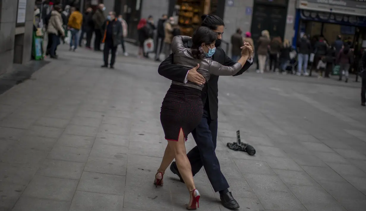 Penari jalanan yang memakai masker menari tango di pusat kota Madrid, Spanyol, Rabu (16/12/2020). Penelitian antibodi yang digelar di seluruh Spanyol menunjukkan satu dari 10 penduduk Spanyol telah terinfeksi oleh virus corona COVID-19 pada paruh kedua bulan November lalu.  (AP Photo/Manu Fernandez)
