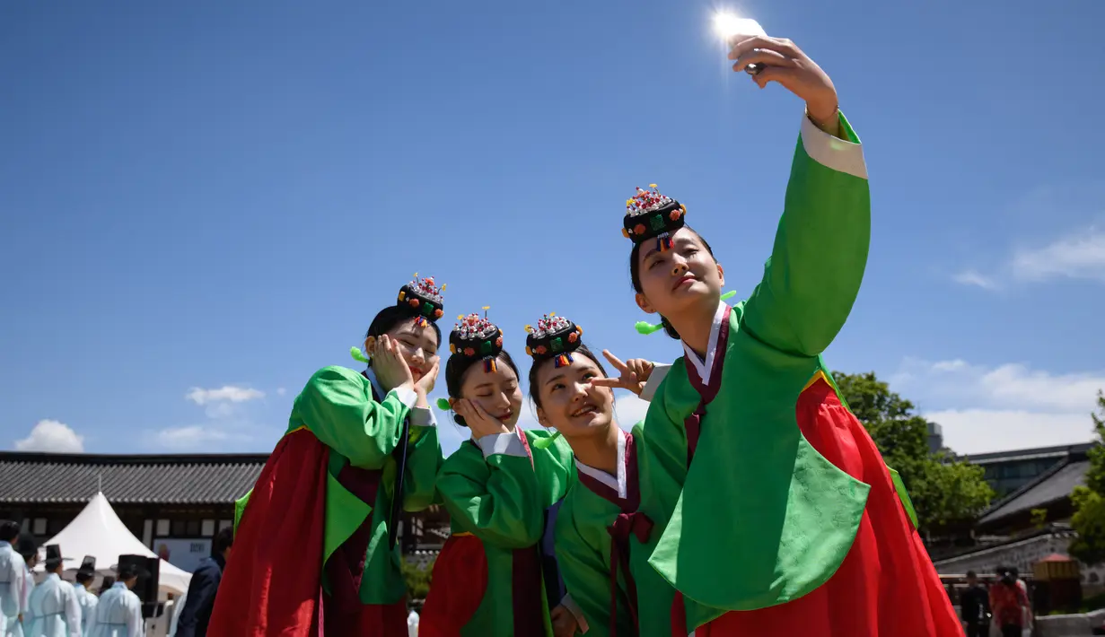 Para wanita muda berswafoto mengenakan pakaian tradisional hanbok setelah upacara “Coming of Age” di Namsan Hanok Village, Seoul, Senin (20/5/2019). Di Korea Selatan, Coming of Age Day atau hari kedewasaan dirayakan secara nasional setiap tahun pada hari Senin ketiga di bulan Mei. (Ed JONES/AFP)