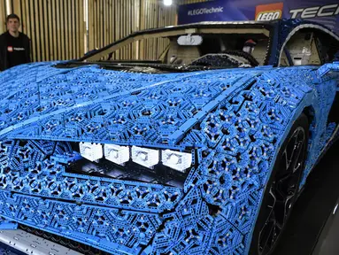 Pengunjung mengamati replika mobil Bugatti Chiron dari jutaan balok Lego Technic pada sebuah pameran di Taman Gorky Moskow, Selasa (23/7/2019). Mobil berwarna biru tersebut dibuat menggunakan lebih dari 1 juta blok Lego Technic dengan berat totalnya sekitar 1.500 kg. (Alexander NEMENOV/AFP)