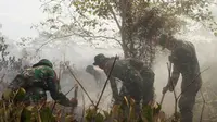 Prajurit Yonif 116/Garda Samudera tengah memadamkan api yang membakar kebun kelapa sawit di Kabupaten Nagan Raya. (Liputan6.com / Rino Abonita)