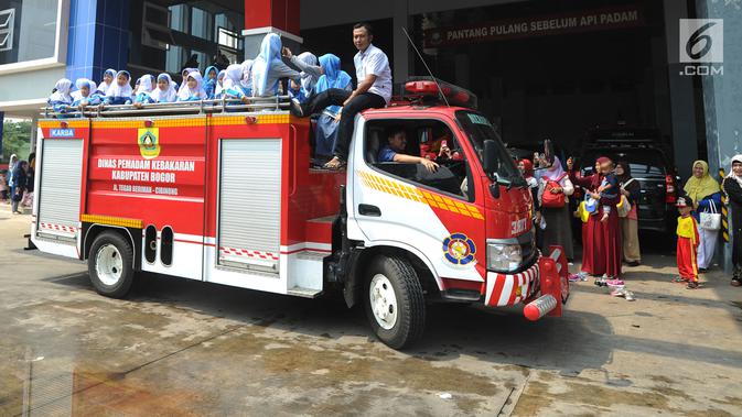 Sejumlah siswa TK di lingkungan Kabupaten Bogor menaiki mobil pemadam kebakaran saat berkunjung ke kantor Dinas Pemadam Kebakaran, Jalan Tegar beriman, Cibinong, Rabu (18/9/2019). Kegiatan belajar di luar kelas ini untuk mengenalkan profesi dan tugas pemadam kebakaran. (merdeka.com/Arie Basuki)
