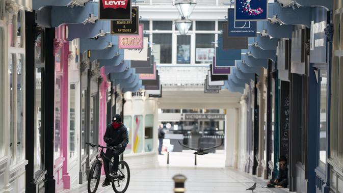 Seorang pria bersepeda melewati deretan toko yang tutup di Leeds, Inggris, pada 5 November 2020. Inggris memasuki karantina wilayah (lockdown) selama sebulan mulai Kamis (5/11) untuk meredam merebaknya kembali penularan virus corona. (Xinhua/Jon Super)
