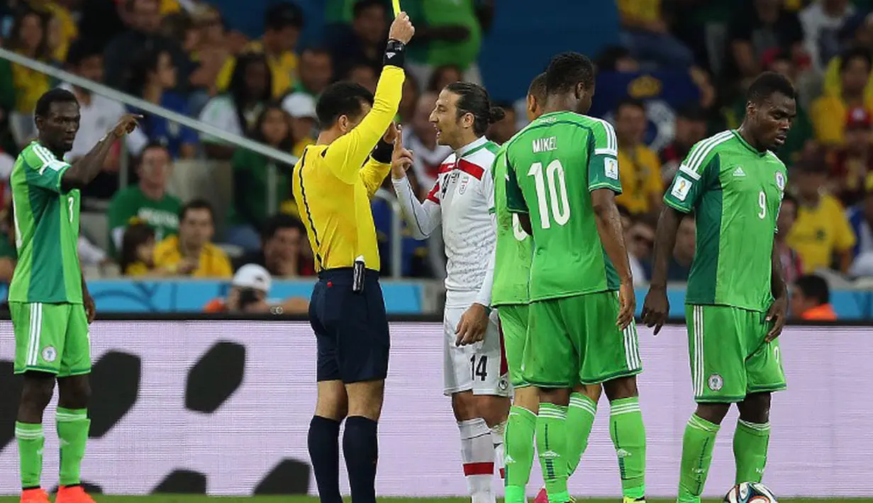 Gelandang Iran, Andranik Teymourian (tengah) harus menerima kartu kuning akibat bermain kasar saat berlaga melawan Nigeria di babak penyisihan Piala Dunia Grup F, Baixada Arena, Brasil, (17/6/2014). (AFP PHOTO/Behrouz Mehri) 