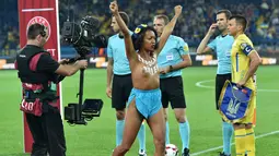 Seorang wanita dari aktivis Femen bertelanjang dada berpose didalam lapangan sebelum pertandingan sepak bola kualifikasi Piala Dunia 2018 antara Ukraina dan Turki di Kharkiv (2/9). (AFP Photo/Sergei Supinsky)