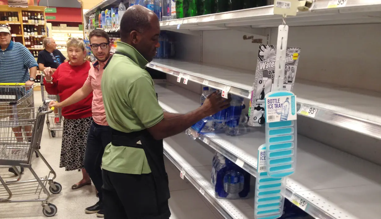 Petugas toko kelontong mengisi ulang air mineral di rak kosong di Surfside, Selasa (5/9). Pasca Florida mengumumkan keadaan darurat menjelang kedatangan badai Irma, warga menyerbu toko untuk memenuhi stok barang kebutuhan mereka. (AP Photo/Alan Diaz)