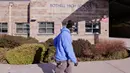 Petugas kebersihan berjalan menuju bagian depan Bothell High School yang ditutup di Bothell, Washington, Kamis (27/2/2020). Sekolah di pinggiran kota Seattle ditutup setelah  anggota keluarga seorang staf sekolah itu dikarantina karena menunjukkan gejala tertular virus corona. (AP/Elaine Thompson)