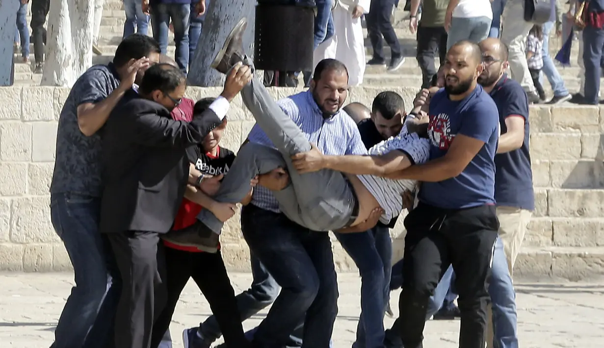Sejumlah warga Palestina membawa seorang pria yang terluka saat bentrok dengan polisi Israel kompleks masjid al-Aqsa di Yerusalem (11/8/2019). Perayaan Idul Adha hari ini juga bertepatan dengan hari libur umat Yahudi yang dikenal dengan Tisha B'av. (AP Photo/Mahmoud Illean)