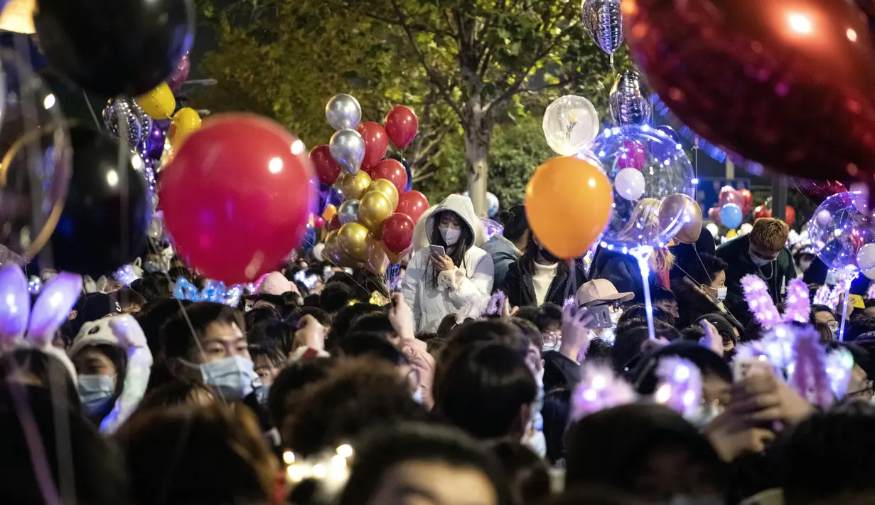 Orang-orang menghadiri  hitung mundur di Wuhan, provinsi Hubei, China (1/1/2021). Banyak yang membawa balon untuk dilepaskan ketika jam menunjukkan pukul 12 pagi. (AFP/Noel Celis)