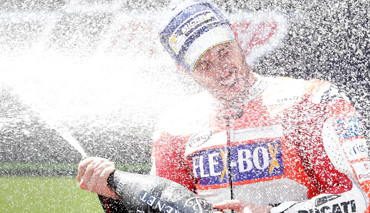 Pembalap Ducati, Andrea Dovizioso menyemprotkan sampanye setelah memenangi MotoGP Catalunya di sirkuit Barcelona Catalunya, Minggu (11/6). Dovizioso menyelesaikan balapan dengan catatan waktu tercepat 44 menit 41,518 detik. (AP Photo/Manu Fernandez)