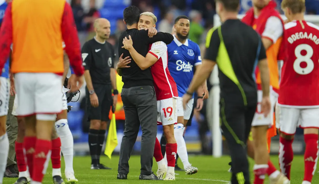 Pemain Arsenal, Leandro Trossard, dipeluk Mikel Arteta setelah laga melawan Everton pada laga Liga Inggris di Stadion Goodison Park, Minggu (17/09/2023). Berkat hasil ini, Arsenal sukses naik ke peringkat empat dengan poin 13 sekaligus meneruskan tren unbeaten mereka di awal musim ini. (AP Photo/Jon Super)