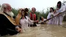 Imam Kristen Ortodoks Serbia membaptis wanita di perairan Sungai Yordan di dekat kota Jericho (4/3). Sungai ini diyakini menjadi tempat Yesus Kristus dibaptis oleh Yohanes Pembaptis.  (AFP Photo/Gali Tibbon)