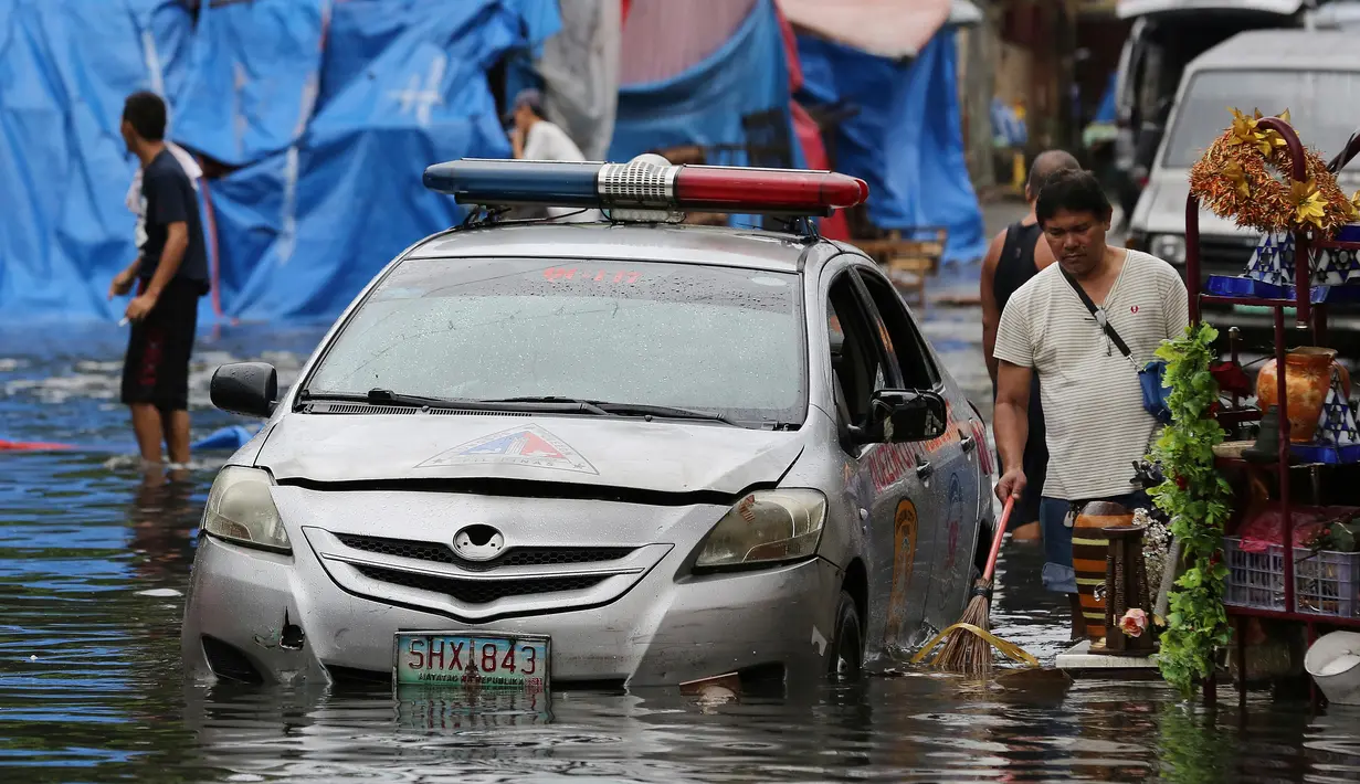 Sebuah mobil polisi terendam banjir yang disebabkan oleh hujan dari Topan Nock-Ten di kota Quezon, utara Manila, Filipina, (26/12). Topan super Nock-ten atau dikenal dengan Nina menerjang Filipina bertepatan saat Natal. (AP Photo / Aaron Favila)