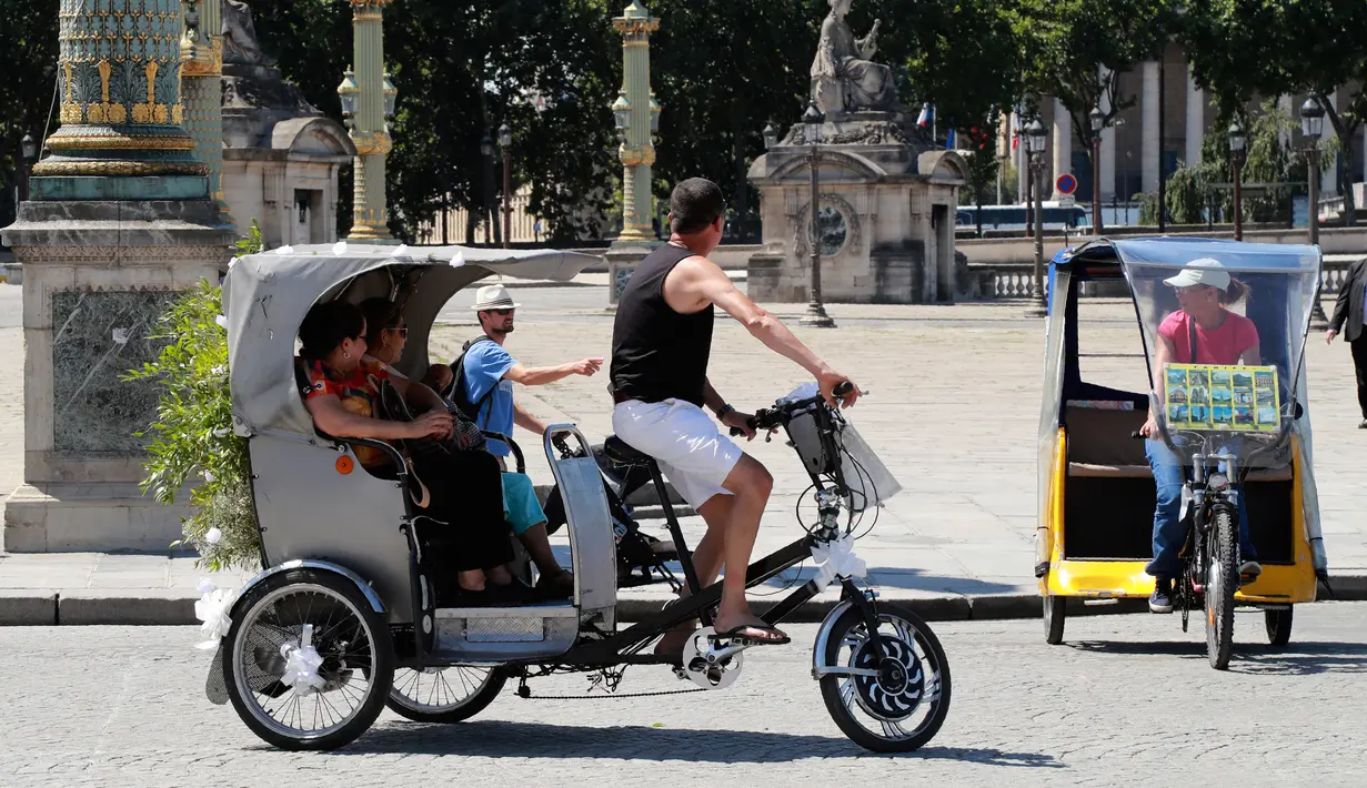 Wisatawan berkeliling kota Paris menggunakan transportasi becak, Prancis, (7/7). Desain becak di Paris ini memiliki posisi penarik becak dibagian depan berbeda dengan becak yang ada di Indonesia. (AFP Photo/Jacques Demarthon)
