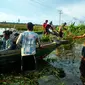 Warga menggunakan perahu untuk menyeberangi Jalan Trans-Kalimantan yang banjir. (Liputan6.com/Rajana K)