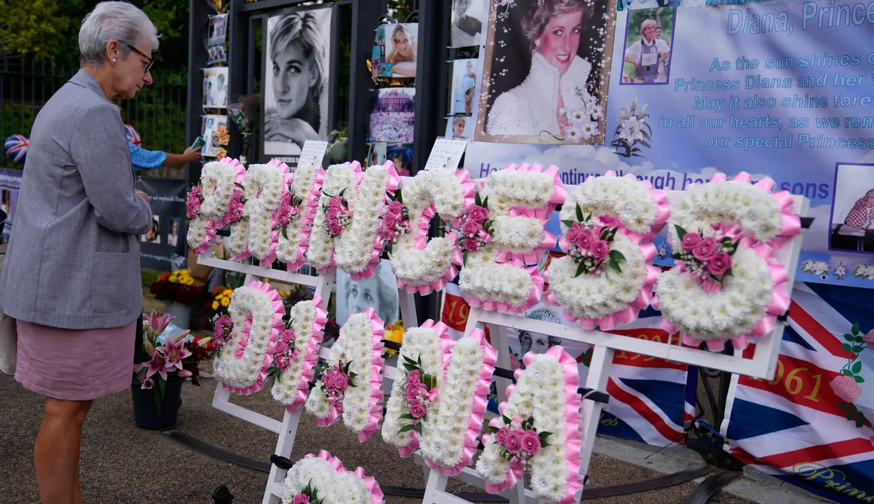 Seorang wanita melihat rangkaian bunga untuk mengenang Putri Diana di luar gerbang Istana Kensington, London, Rabu (31/8/2022). Hari ini menandai peringatan 25 tahun kematian Putri Diana dalam kecelakaan mobil di Paris. (AP Photo/Alastair Grant)