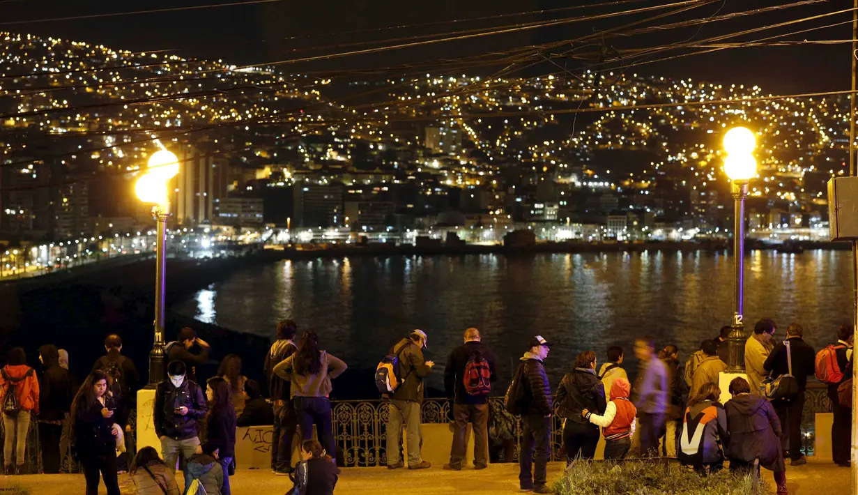Warga berdiri dan melihat ke laut di Bukit Cerro Barron di kota Valpraiso usai gempa 8,3 SR, Chile, Rabu (16/9).  Menurut laporan dari otoritas setempat, gempa itu berpotensi memicu tsunami yang akan melanda Chile dan Peru.  (REUTERS/Rodrigo Garrido)