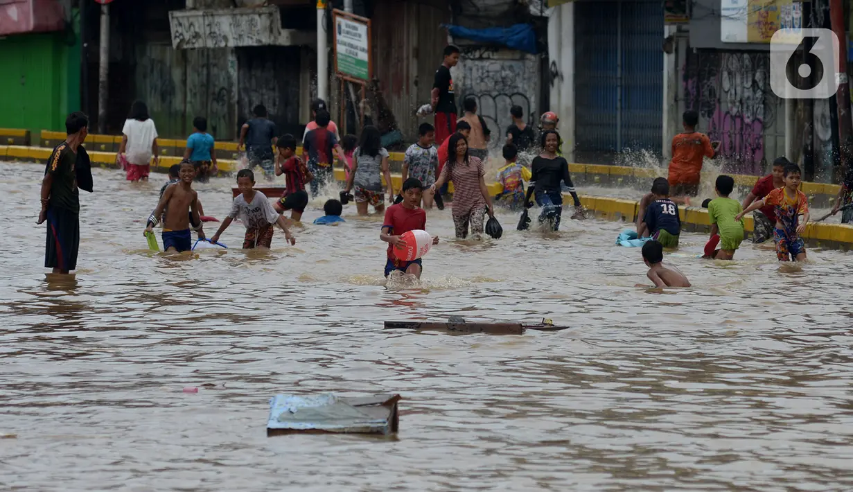 Anak-anak bermain air saat banjir menggenangi Jalan Jatinegara Barat, Jakarta, Kamis (2/1/2020). Hujan yang terjadi kemarin malam membuat Kali Ciliwung meluap ke jalan. (merdeka.com/Imam Buhori)