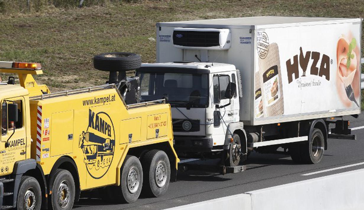 Sebuah truk yang berisi sekitar 50 imigran gelap yang tewas siap diderek dari jalan tol di Austria, dekat perbatasan Hongaria, Kamis (27/8/2015). Indikasi awal mereka tewas karena kekurangan oksigen. (AFP PHOTO/Dieter NAGL)