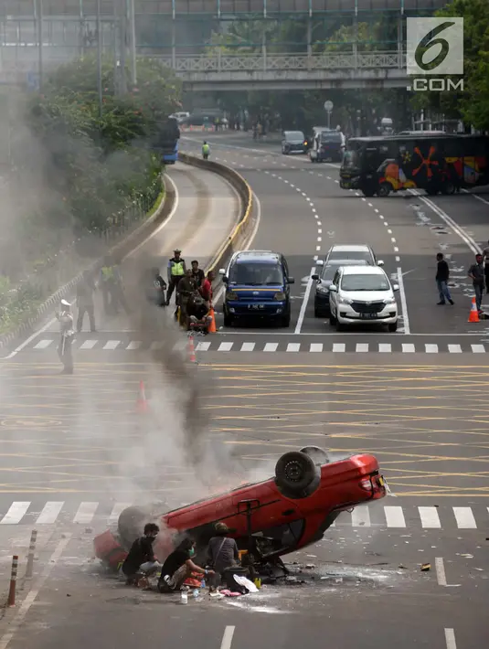 Sebuah mobil terguling dalam adegan syuting film dokumenter di kawasan Sarinah, Jalan MH Thamrin, Jakarta Pusat, Sabtu (14/4). Untuk keperluan syuting, arus lalu lintas menuju Sarinah dan Thamrin dialihkan menuju KH Mas Mansyur. (Merdeka.com/Imam Buhori)