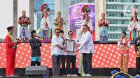 Perhelatan budaya ini mendapat penghargaan dari Museum Rekor Dunia Indonesia (MURI). Tampak dalam foto, Gubernur DKI Jakarta Pramono Anung dan Wakil Gubernur Rano Karno menunjukan piagam Rekor MURI saat pertunjukan kolosal budaya pada Hari Bebas Kendaraan Bermotor (HBKB) atau Car Free Day (CFD)di kawasan Bundaran Hotel Indonesia (HI), Jakarta, Minggu (6/7/2025). (Liputan6.com/Angga Yuniar)