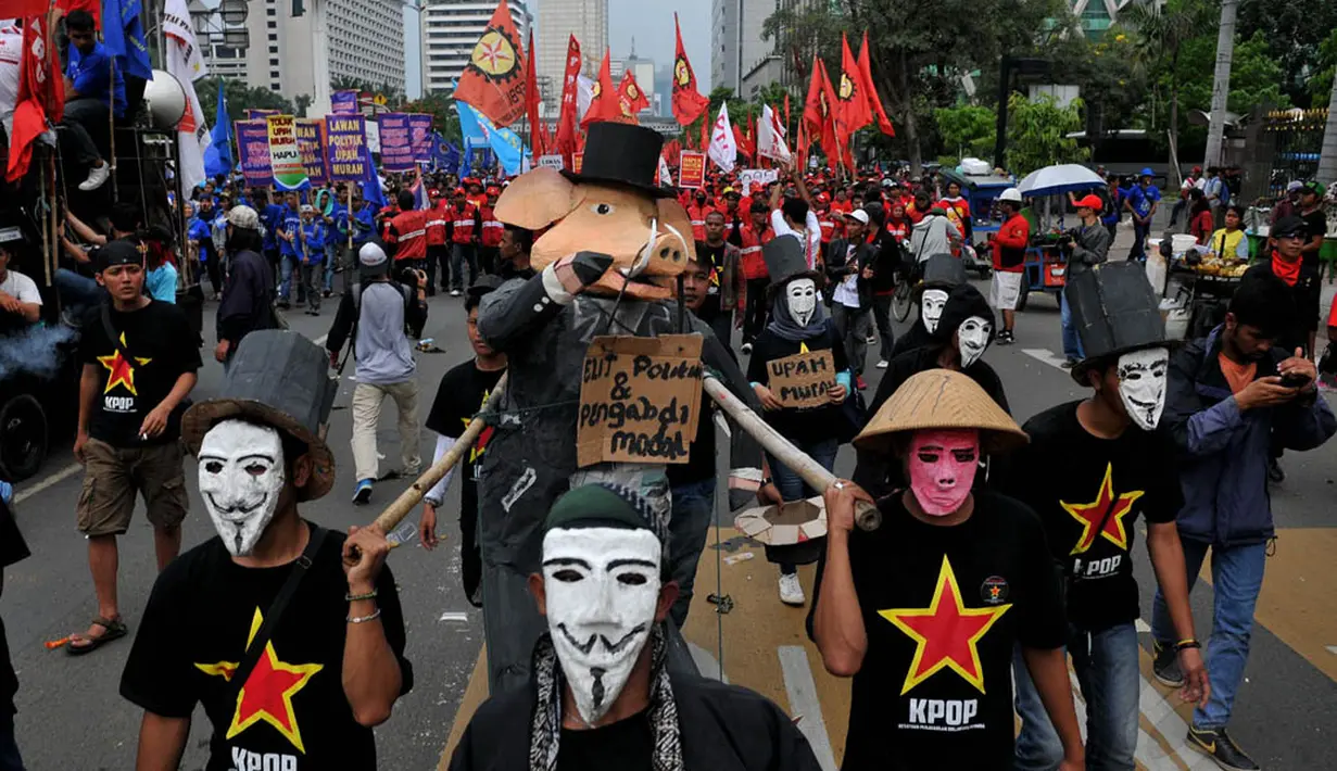 Beberapa buruh berpakaian hitam dan memakai topeng terlihat menggotong boneka babi yang dikalungkan tulisan "Elit Politik & Pengabdi Modal", Kamis (1/5/14). (Liputan6.com/Johan Tallo)