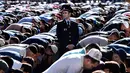 Seorang polisi berdiri di antara ratusan muslim Rusia yang tengah melaksanakan salat Idul Fitri di luar masjid di pusat kota Moskow, Selasa (5/7). Perayaan Idul Fitri 1437 H di Rusia jatuh pada hari ini. (Kirill KUDRYAVTSEV/AFP)