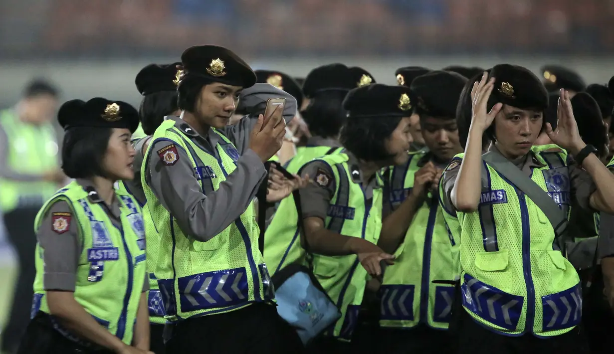 Polwan (Polisi Wanita) merapikan seragam sebelum pengarahan usai pengamanan di Stadion Si Jalak Harupat, Bandung, Minggu (25/10/2015). (Bola.com / Nicklas Hanoatubun)