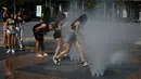 Orang-orang mendinginkan diri di air mancur di Pamplona, Spanyol, 15 Juni 2022. Layanan cuaca Spanyol mengatakan massa udara panas dari Afrika Utara memicu gelombang panas besar pertama di negara itu tahun ini dengan suhu diperkirakan akan meningkat menjadi 43 derajat Celcius (109 derajat Fahrenheit) di area tertentu. (AP Photo/Alvaro Barrientos)