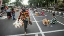 Warga melintasi pedagang yang  sedang menunggu pembeli di dalam garis petak-petak untuk menerapkan jaga jarak (physical distancing) di sepanjang jalan di Surabaya, Selasa (2/6/2020). Garis petak-petak bagi pedagang itu sebagai langkah pencegahan penyebaran COVID-19. (Photo by Juni Kriswanto / AFP)